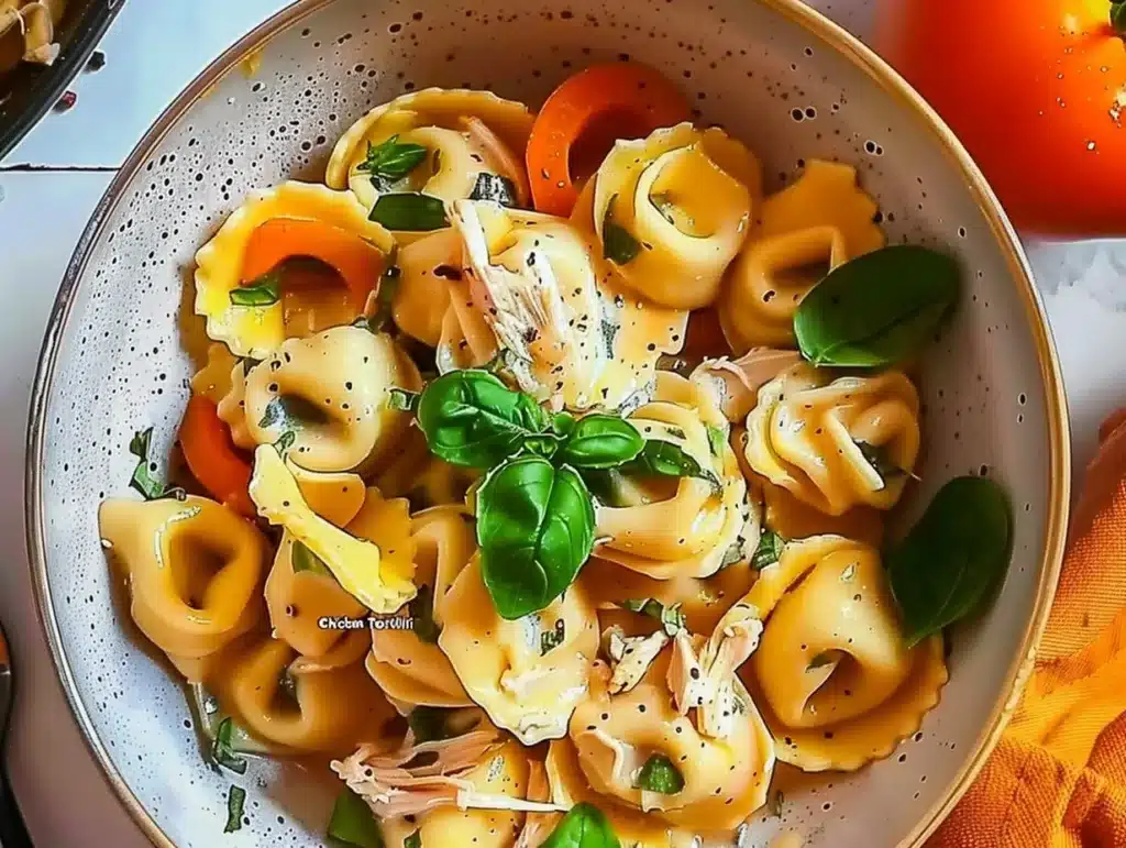 CrockPot Chicken Tortellini in a bowl with fresh herbs and cheese on top