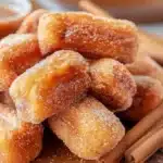 Healthy air fryer churro bites sprinkled with cinnamon and sugar on a plate.