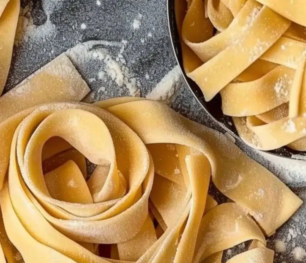 A close-up of fresh homemade pasta dough on a wooden surface.