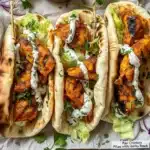 Sheet pan chicken pitas with herby ranch on a wooden table.